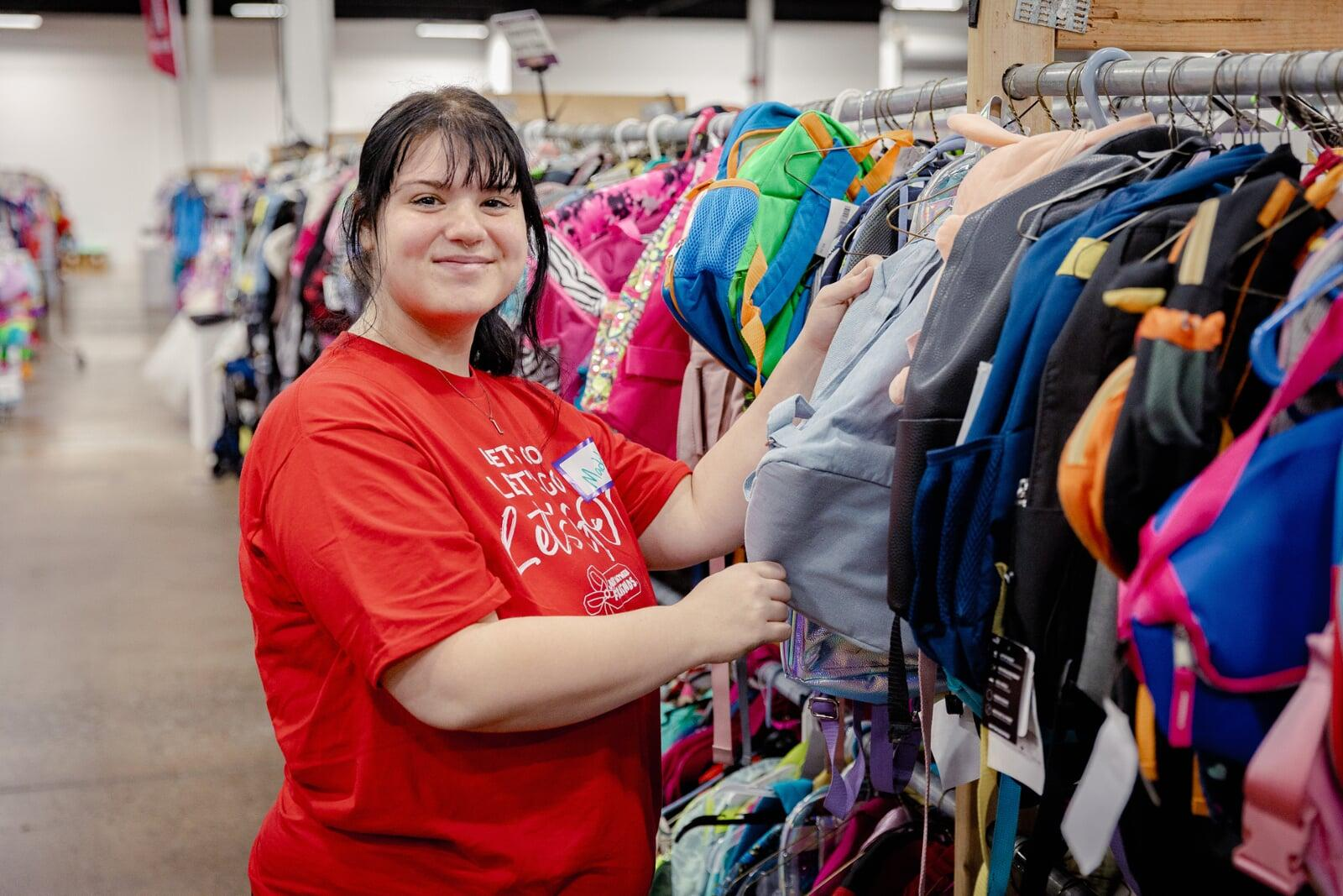 A smiling Team Member stands behind a rack of toddler girl's clothing at the sale.