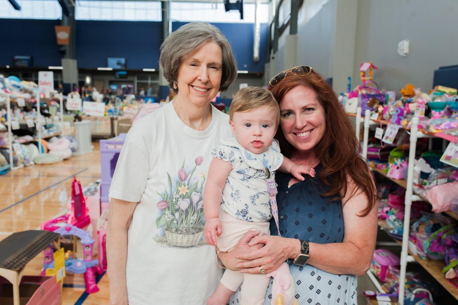 A mom and her two kids stand in the shoe section for a happy family photo.